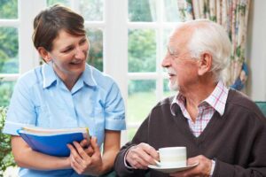 A caregiver assisting an older adult with medication in a comfortable residential living space.